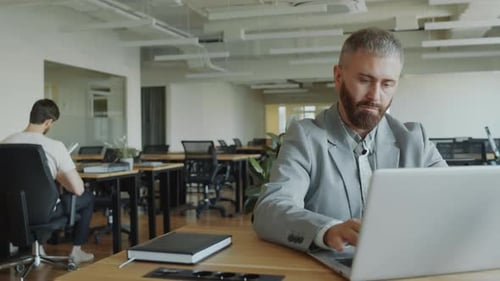 Businessman Working on Laptop at Desk in Office