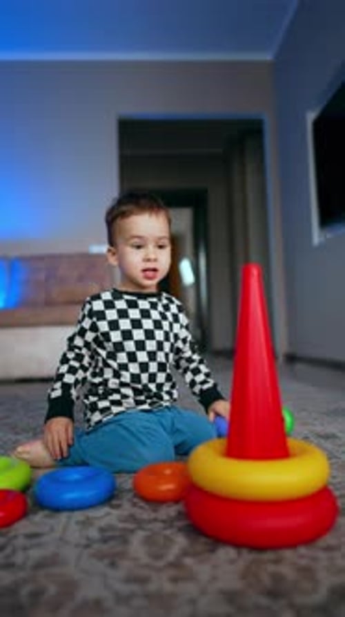Encantador niño de dos años sentado en el suelo construyendo una pirámide.