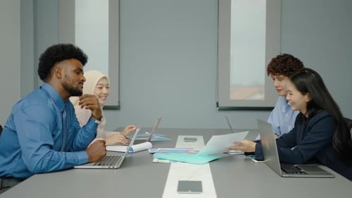 Professionals Collaborating on Laptop and Documents