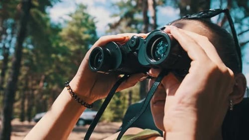 Woman Looking Through Binoculars in the Forest