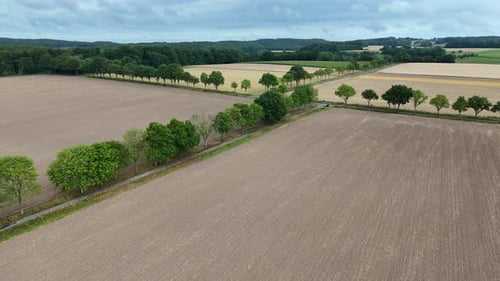 Parking car on street between grown harvested farm fields in summer. Aerial approaching shot. Cultiv