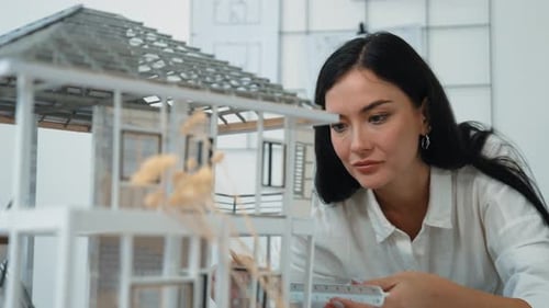 Architect using ruler to measure house model at modern office. Immaculate.