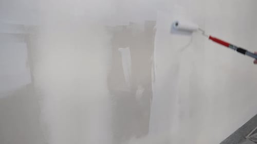 Man Painting Gray Wall With White Paint