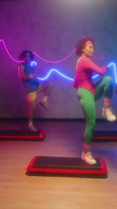 Active Sportspeople Performing Aerobics Steps in Neon Studio