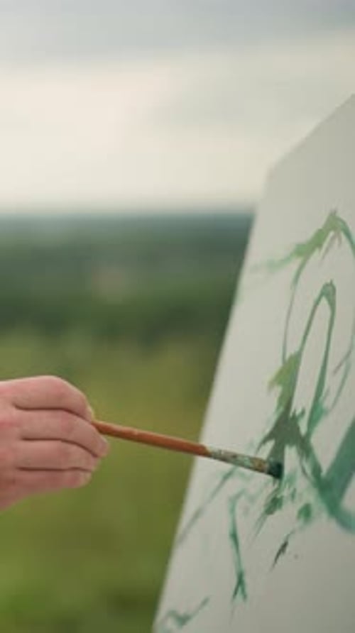 Hand Painting Outdoors with Green Paint on Canvas