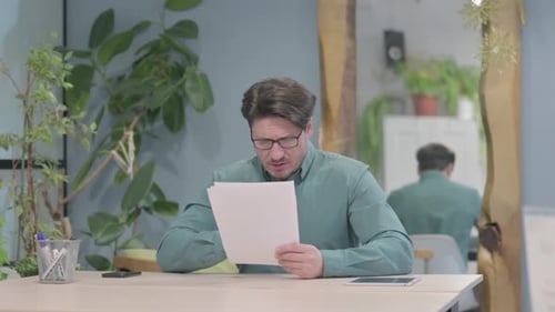 Man Reviews Documents at Desk Indoors