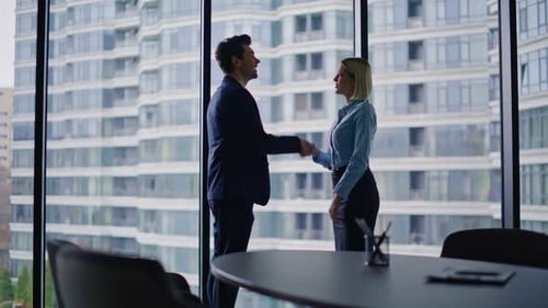 Confident Businessman Shaking Hands with Woman Executive in Modern Office