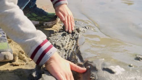 Closeup of little boy playing on beach with sand and water