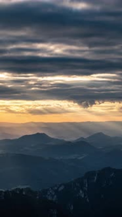 Sun Shining Through Clouds Over Mountain Landscape