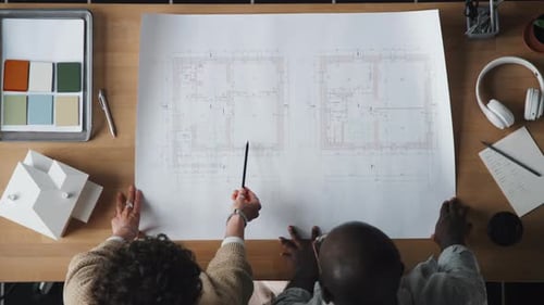 Architects Reviewing Blueprints at Wooden Desk