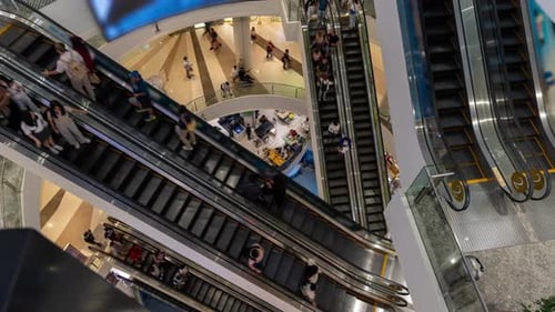timelapse Elevated view of a busy mall interior with multiple escalators and shoppers