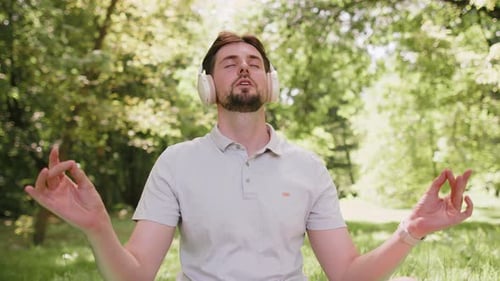 Young Man Sitting on Mat in Lotus Position Relaxing in City Park on Summer Day Meditation Relax
