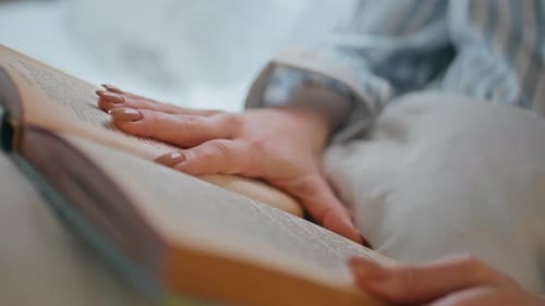 Person Reading a Book in Bed Close Up