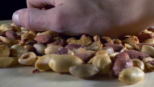 Hand Reaching into pile of Assorted Nuts