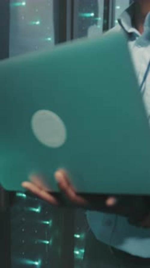 Data Center Technician Working with Laptop in Server Room