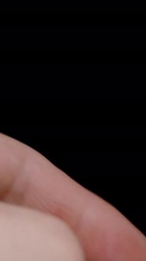 Vertical video. A green almond in a man's hand, he puts it down, takes a half and examines the inner