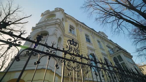 Grand Building with Architectural Details Stands Behind Ornate Iron Fence