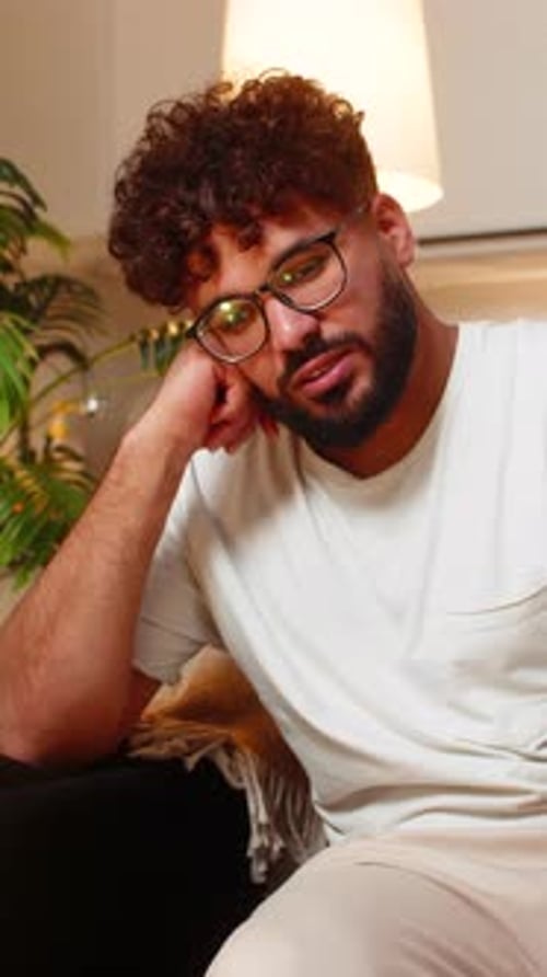 Man with Glasses Sits and Rests Head on Hand