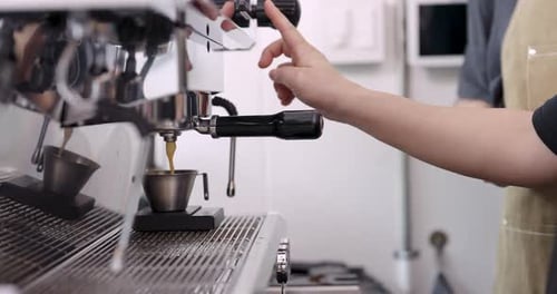 Barista hand pressing button on espresso machine to start brewing process in cafe, mechanical parts