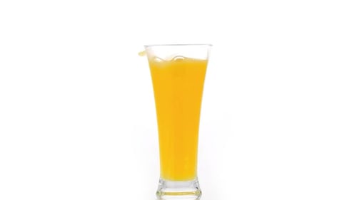 Tall Glass of Yellow Juice Splashing Slightly