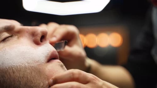 Barber Shaves Adult Man's Face with Straight Razor