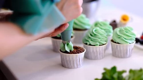 Person Frosting Green Cupcakes with Piping Bag