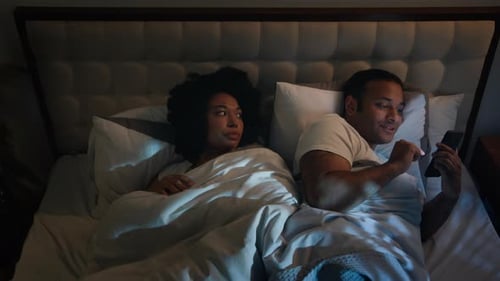 Novia afroamericana irritada y enojada que intenta dormir, empuja al hombre, novio, esposo, usando