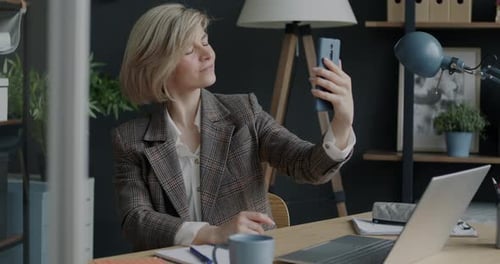 Portrait of Happy Businesswoman Taking Selfie with Smartphone Posing and Smiling Indoors in Office