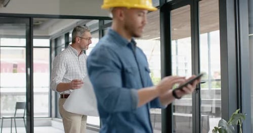 Diverse male and female architects discussing over a plan at office