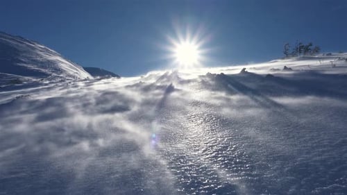 Der Wind bläst Schnee in den gefrorenen Alpen, an windigen Tagen in der Winternatur