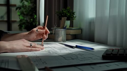 Hände, die mit Werkzeugen und Bleistift einen architektonischen Entwurf erstellen