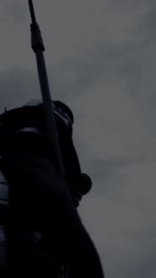 A Silhouetted Warrior Holding a Spear Positioned Against a Dramatic and Cloudy Sky Landscape