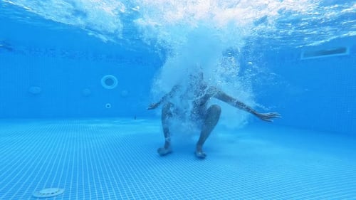 Man jumps under water in the pool.
