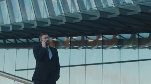 Sharply Dressed Businessman, Having Phone Conversation Outside Glass Building