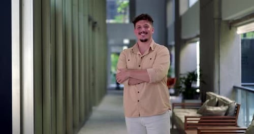 Smiling Man with Arms Crossed in Modern Setting
