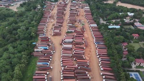 An aerial drone view of a massive fleet of commercial trucks parked in neat rows in a large depot.