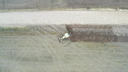 Aerial top down ascend over tractor excavator dig drainage trench near road