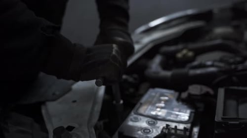 Close up of hands tightening screws on car engine