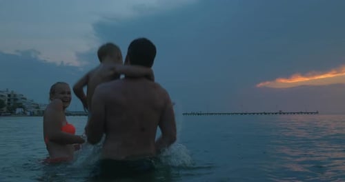 Young family enjoying sea bathing in the evening