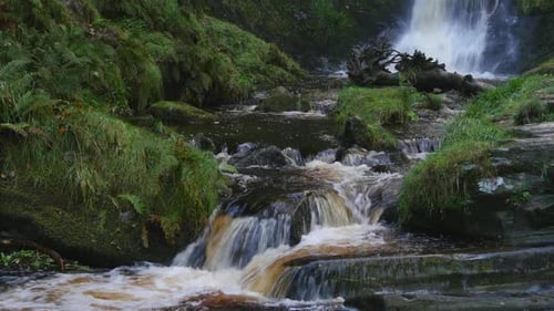 A lovely stream with flowing water over the rocks at the base of Pistyll Rhaeadr Falls, It's the hi