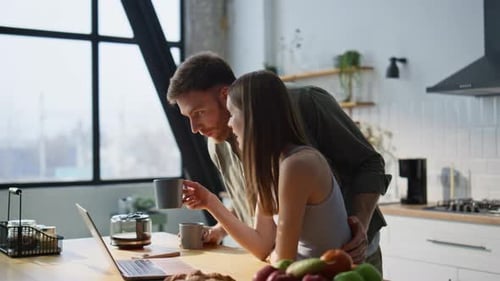 Couple Sharing Coffee and Laptop in Modern Kitchen