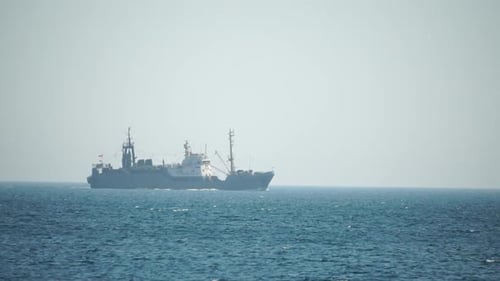 Fishing Boat Trawler Catches Fish While Sailing on Sea A Commercial Fishing Boat on the Horizon in a