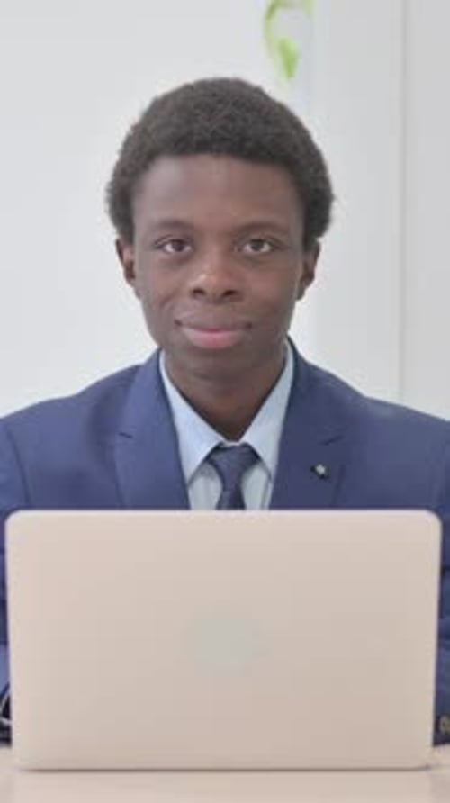 Young Man Smiling While Working on Laptop