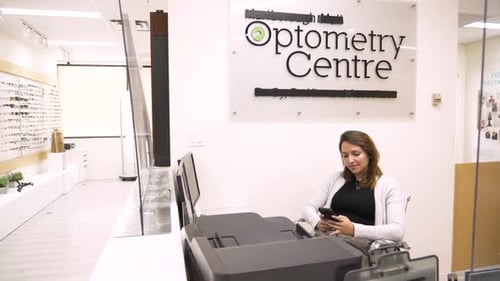 Receptionist Texting at Optometry Center Front Desk