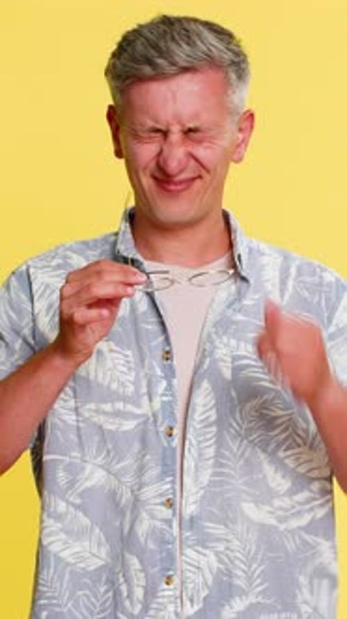 Man Takes Off Glasses, Rubbing Irritated Eye, Yellow Background