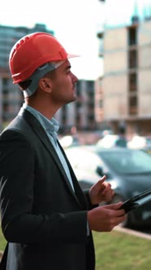 Vertical of Architect Looking Tablet Pc and Comparing Project with Building