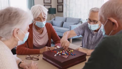 Seniors Enjoy Game Together Indoors While Wearing Masks