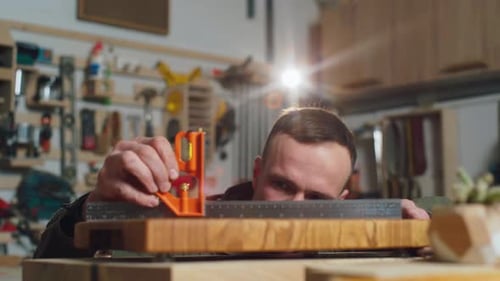 Man Measuring Wood in Workshop with Tools