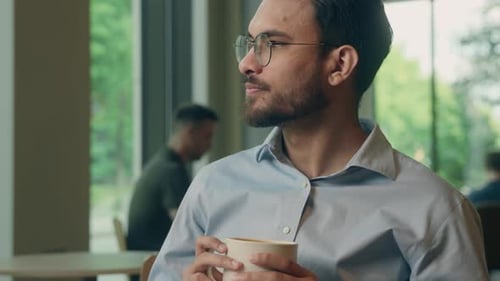 Man Drinks Coffee in Modern Cafe Setting
