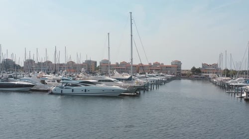 Cinematic drone / aerial tracking circling shot of motor and sailing boats of a marina / port with w